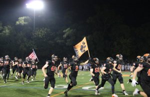 The wildcats sprint onto the field to initiate the second home game of the season against Lake Zurich. Senior Mason Strader (2) proudly holds the Wildcat flag.