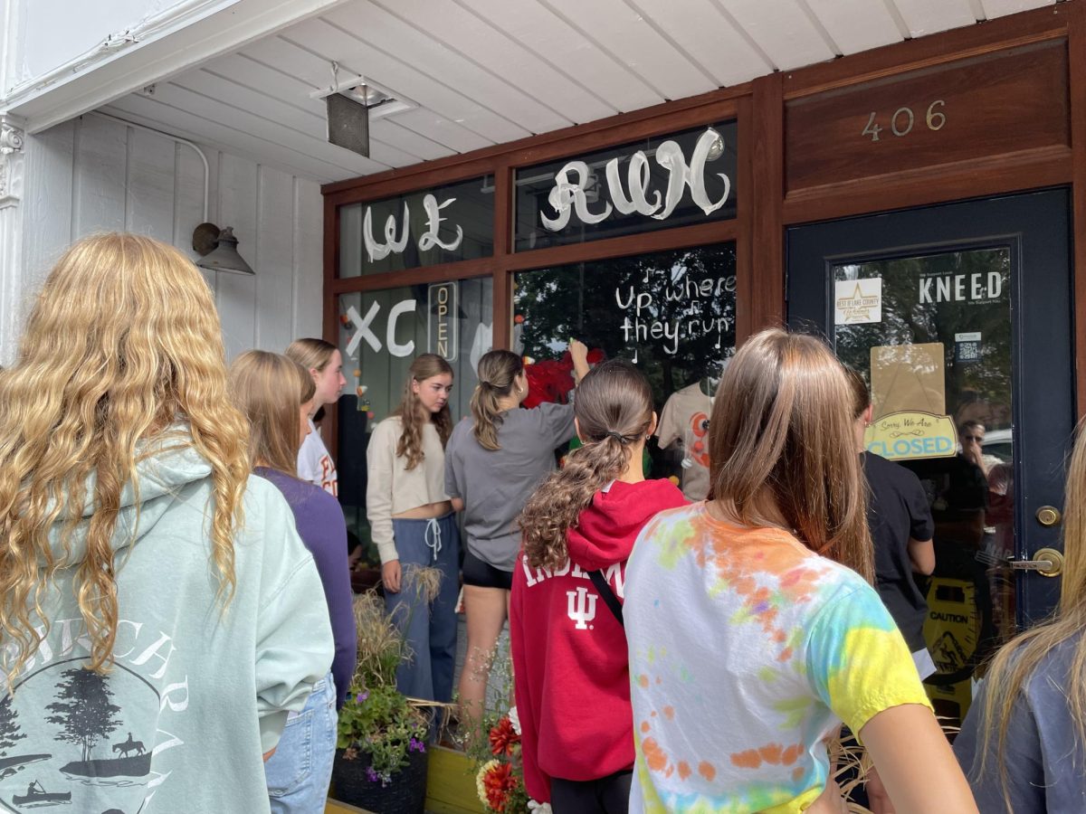 Students gather at Downtown Libertyville to decorate windows for homecoming week