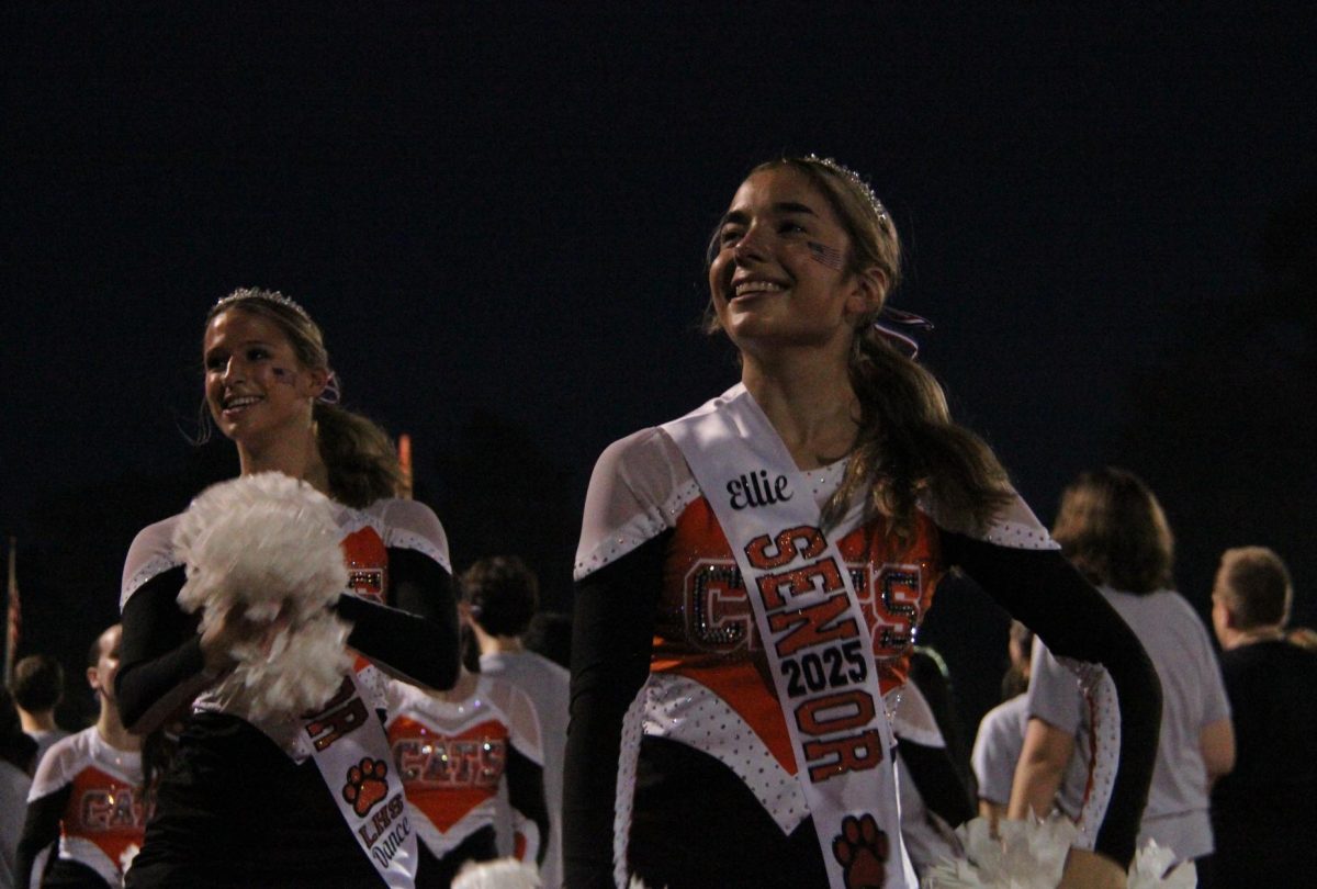 Senior Ellie Perrone beams up to the student section while performing a routine with the Poms team. 